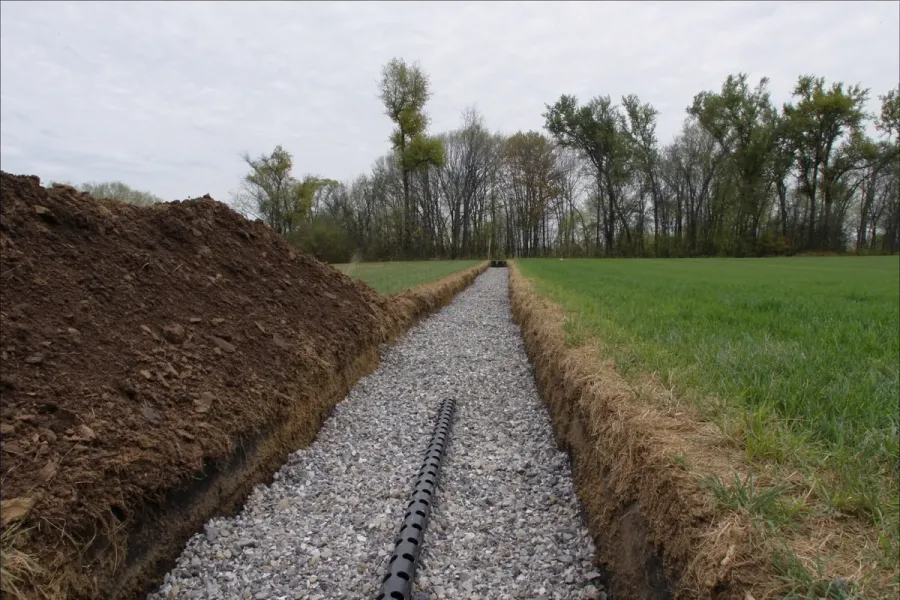 A gravel-bedded drainfield trench open in an Indiana yard before it is covered